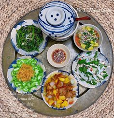 a tray with bowls and plates filled with food on top of it, sitting on a woven place mat