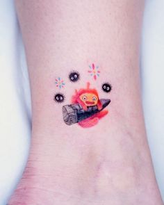 a small tattoo on the ankle of a girl with an orange and black object in her hand