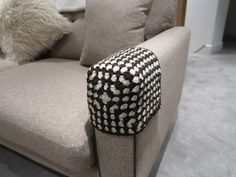 a white and black pillow sitting on top of a couch next to a gray chair