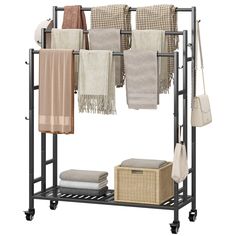 an iron rack with towels and baskets on wheels for drying clothes, blankets or other items