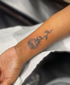 a woman's arm with a rose tattoo on the left side of her wrist