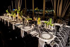 a long table is set up with black and white linens for an elegant dinner