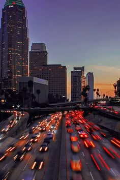 the city skyline is lit up at night, with many cars moving on the road