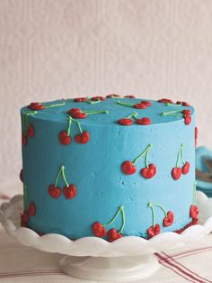 a blue cake with cherries on it