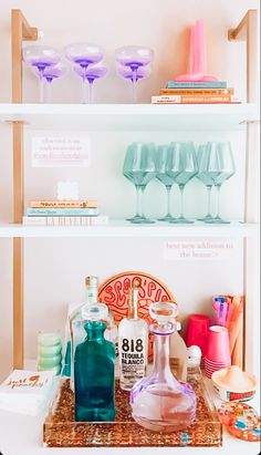 the shelves are filled with bottles, glasses and other decorative items for sale in front of them