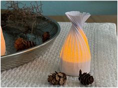 two pine cones sitting on top of a table next to a vase and candle holder