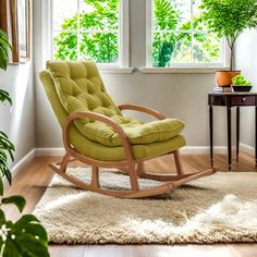 a green rocking chair sitting in front of a window next to a table with a potted plant on it