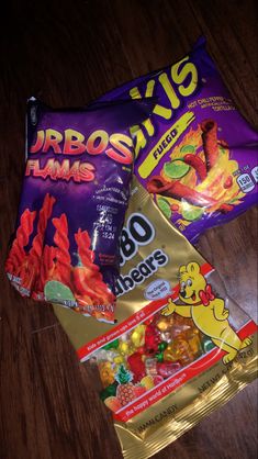 three bags of candy sitting on top of a wooden table