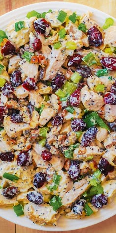 a white plate topped with chicken and cranberries on top of a wooden table