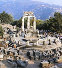 the ruins are surrounded by large rocks and trees, with mountains in the back ground