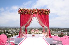 an outdoor wedding setup with pink umbrellas and flowers