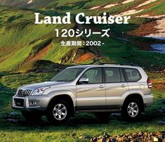 a silver suv parked on top of a lush green hillside next to the ocean with text that reads land cruiser