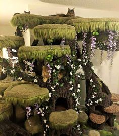 there is a cat sitting on top of the moss covered tree house that has flowers growing all over it