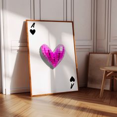 a pink heart cut out of paper sitting on top of a wooden floor next to a chair