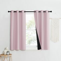 a window with pink curtains hanging on the side and a white wall in the background