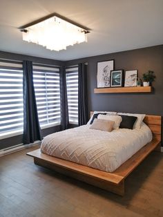 a bed sitting in the middle of a bedroom next to two windows with blinds on them