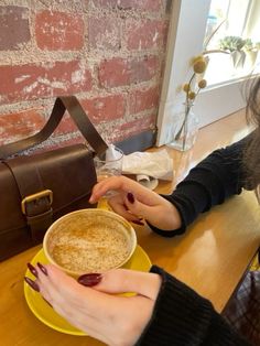 a woman sitting at a table with a cup of coffee in front of her and a handbag behind her