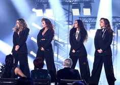 four women in black outfits on stage at a concert