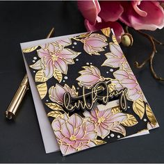 a close up of a card with flowers on it and a pen next to it