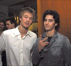 two young men standing next to each other in front of a mirror with one pointing at the camera