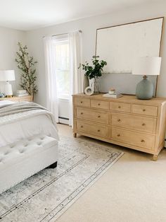 a bedroom with a bed, dresser and large mirror in it's centerpiece