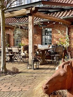 a horse statue is in front of a brick building with an outdoor dining table and chairs