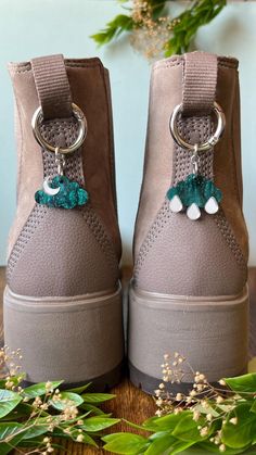 a pair of gray shoes with green and white pom poms