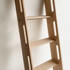 a wooden ladder leaning up against a white wall with holes in the bottom part of it