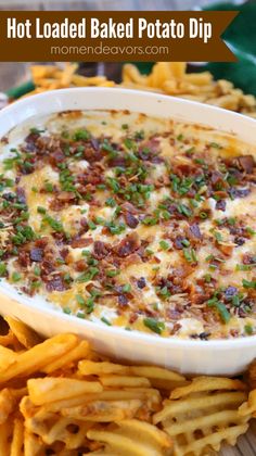 hot loaded baked potato dip in a white bowl surrounded by french fries on a wooden table