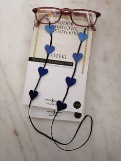 a pair of eyeglasses with blue hearts attached to them on top of a book