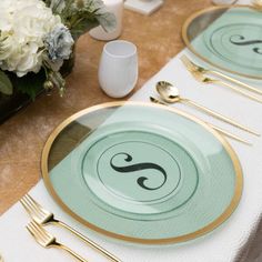 the table is set with gold and green plates, silverware, and white flowers