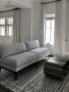 a living room filled with furniture and large windows next to a rug on the floor