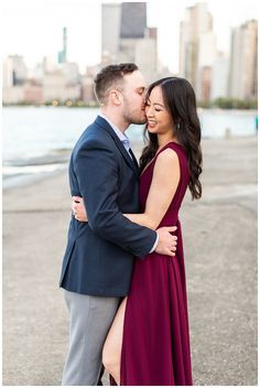 a man and woman standing next to each other in front of a body of water