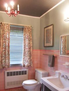 a bathroom with pink tile walls and white fixtures, including a window over the toilet