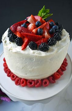 a cake with berries and strawberries on top is sitting on a white platter