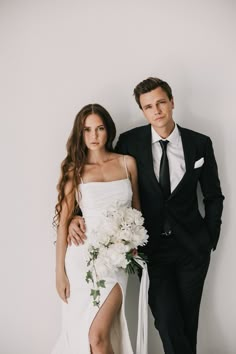 a man and woman in formal wear posing for a photo with flowers on their wedding day