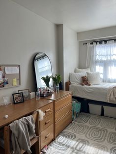 a bedroom with a bed, dresser and mirror on the wall next to a window