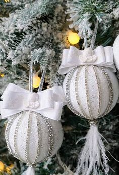 two white ornaments hanging from a christmas tree