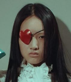 a woman with a red heart on her forehead and eye patch in front of her face