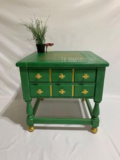 a small green table with gold trimmings and a potted plant on top