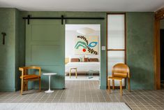 a room with green walls and two chairs in front of the door that leads to another room