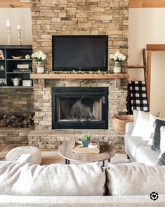 a living room with a couch, coffee table and television on the fireplace mantel