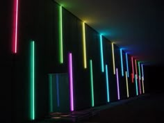 neon lights are lit up on the wall in this dark room with black walls and flooring