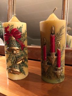 two candles are sitting next to each other on a wooden table with a mirror in the background