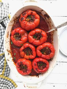 a pan filled with cooked red peppers and sauce on top of a white wooden table