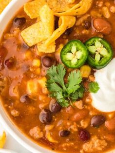 a white bowl filled with chili, beans and tortilla chips