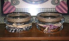 two glass jars sitting on top of a wooden table next to a framed picture and some twine ribbons