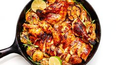 a pan filled with chicken and lemons on top of a white countertop next to a red frame