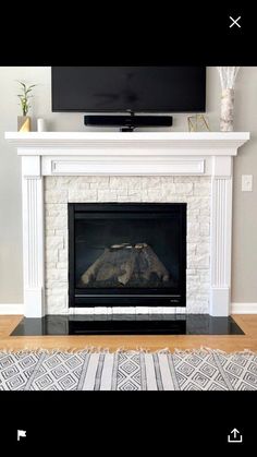 a white fireplace with a flat screen tv above it and a rug on the floor