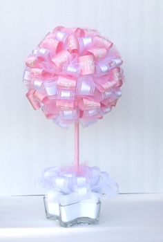 a pink lollipop candy tree on a white table with ribbon around the base